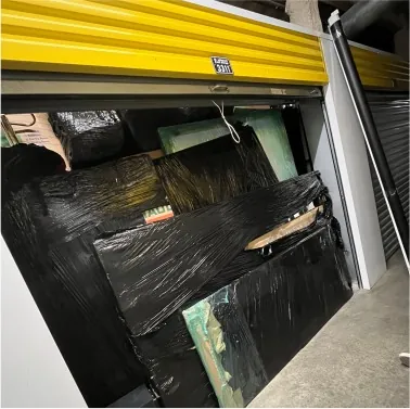 Storage unit packed with large items shrink-wrapped in black plastic