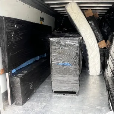 Inside a box truck loaded with shrink-wrapped furniture and a covered mattress